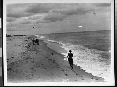 A Woman In A Bathing Outfit Running Towards A Group Of Four People By The Shore At Belmar, Nj by Wallace G. Levison Pricing Limited Edition Print image