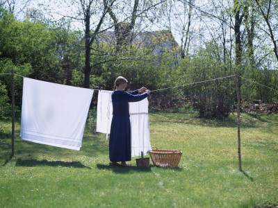A Young Woman Hanging Out Laundry, Smaland In Sweden by Berndt-Joel Gunnarsson Pricing Limited Edition Print image