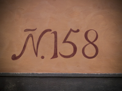 Painted House Number On A Terracotta Coloured Rendered Wall by Olwen Croft Pricing Limited Edition Print image
