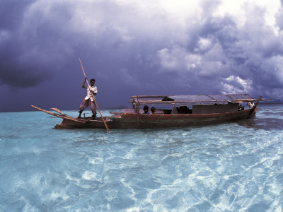 Bajau Fisherman In Traditional Lepa Boat With Rain Clouds Behind, Pulau Gaya, Borneo, Malaysia by Jurgen Freund Pricing Limited Edition Print image