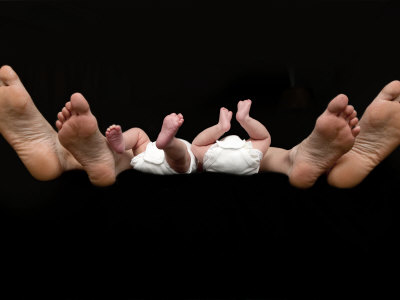 Feet Of Caucasian Family, Parents And Twin Babies Against Black Background by Images Monsoon Pricing Limited Edition Print image