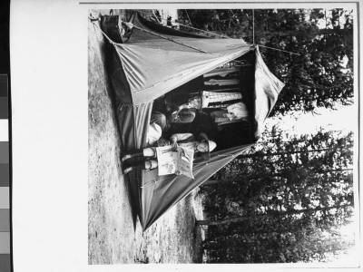 Puffing On Cigarette As His Wife Reads Newpaper Camping At Yellowstone Nationalpark by Alfred Eisenstaedt Pricing Limited Edition Print image