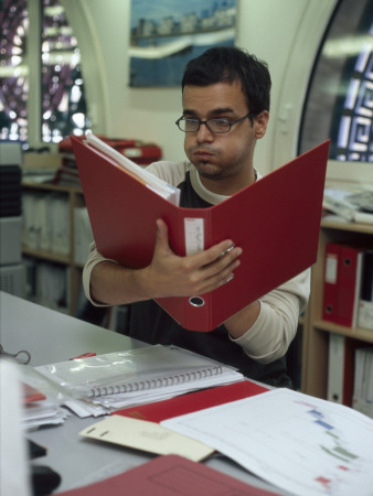 Office Life And Interiors, Office Worker At Desk Puffing His Cheeks by Nicholas Kane Pricing Limited Edition Print image