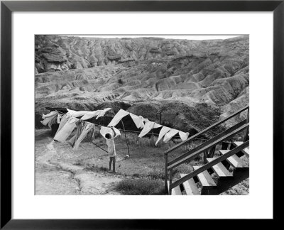 Woman Hanging Laundry With Land Erosion In The Background by Alfred Eisenstaedt Pricing Limited Edition Print image