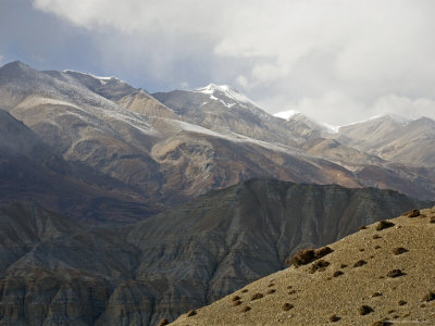 Colorful Dry Hills In Mustang, Nepal With A Snowy Mist In The Sky by Stephen Sharnoff Pricing Limited Edition Print image