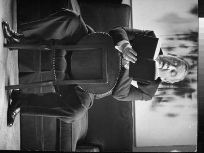 Charles Laughton Reading Aloud From Book While Straddling A Chair by Alfred Eisenstaedt Pricing Limited Edition Print image