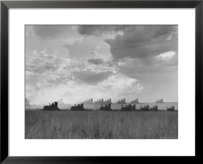 Wheat Harvest Time With Two Lines Of Combines Lining Up In Field With Threatening Sky by Joe Scherschel Pricing Limited Edition Print image