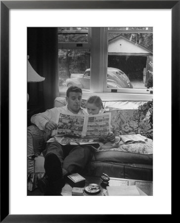 Father Sitting On Couch With Pigtailled Daughter Reading To Her The Sunday Comic Pages by Nina Leen Pricing Limited Edition Print image