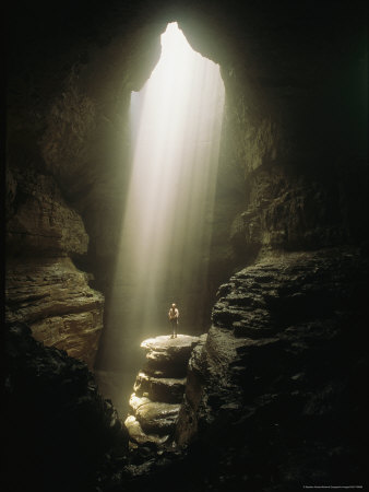 Natural Light Illuminates A Person Standing The Bottom Of A Cave by Stephen Alvarez Pricing Limited Edition Print image