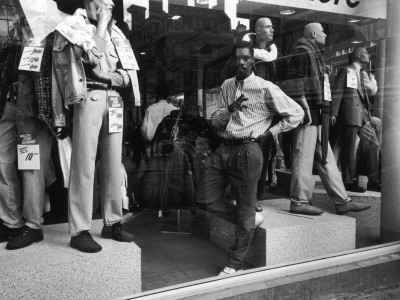Male Store Attendant In A Clothes Shop Window by Shirley Baker Pricing Limited Edition Print image