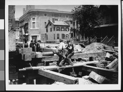 Two Workmen Screwing The House Back At A Construction Site On A Residential Street by Wallace G. Levison Pricing Limited Edition Print image