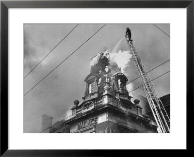 Fireman On Ladder Using A Hose To Extinguish Blazing Building Set Afire by Hans Wild Pricing Limited Edition Print image