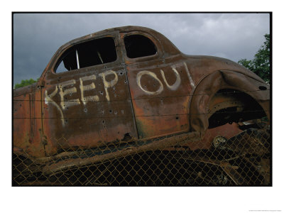 Remains Of An Old Car With A Keep Out Sign Painted On Its Side by Annie Griffiths Belt Pricing Limited Edition Print image