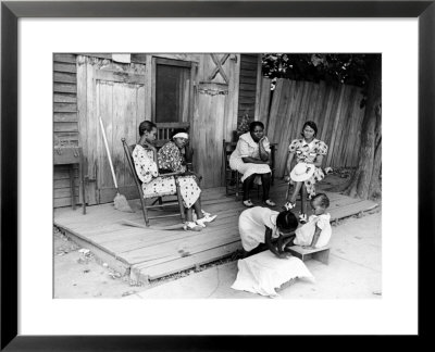 African American Women Sitting On The Porch Of Their Ramshackle House Watching Their Children Play by Alfred Eisenstaedt Pricing Limited Edition Print image