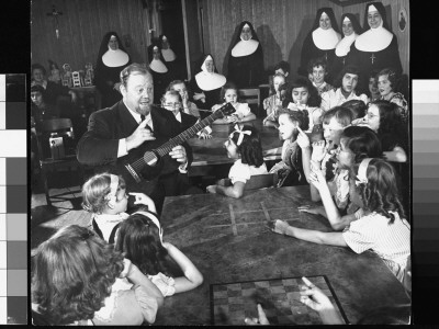 Balladeer Burl Ives Playing Guitar, Singing Amidst Group Of Girls As Nuns Look On by Wallace Kirkland Pricing Limited Edition Print image