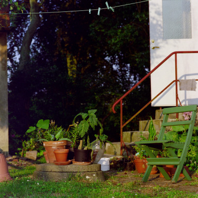 Potted Plants And A Folding Chair Outside A House by Mikael Leijon Pricing Limited Edition Print image