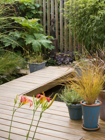 Decked Terrace And Walkway Beside Pond With Containers And Ethnic Sculpture, Designer: Kathy Taylor by Clive Nichols Pricing Limited Edition Print image