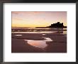 Bamburgh Castle In Silhouette At Sunrise, With Rock Pools On Empty Beach, Northumberland, England by Lee Frost Limited Edition Print