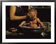 A Bhutanese Woman Bathes Her Baby In A Large Metal Bowl by James L. Stanfield Limited Edition Print