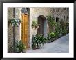 Flower Pots And Potted Plants Decorate A Narrow Street In Tuscan Village, Pienza, Italy by Dennis Flaherty Limited Edition Print