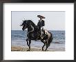 Horseman In Traditional Dress Riding Black Andalusian Stallion On Beach, Ojai, California, Usa by Carol Walker Limited Edition Print