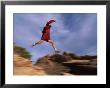 A Runner Leaps Across Rocks In Moab, Utah by Bill Hatcher Limited Edition Print