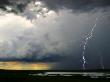 Lightning Cracks In A Cloud-Filled Sky With Rain Falling In Distance by Randy Olson Limited Edition Print