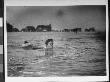 A Woman Making A Face As She Dogs Paddles In The Water At The Beach by Wallace G. Levison Limited Edition Print