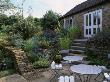 Patio With Metal Chairs And Tables, Stone Wallls Planted With Achilleas, And Phormium by Clive Nichols Limited Edition Print