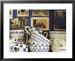Blue And White Crockery In Front Of Wall With Photographs by Michael Paul Limited Edition Print