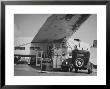 Service Attendant Pumping Gasoline Into Ford Sedan As Woman Watches At Gas Pumps by Peter Stackpole Limited Edition Print