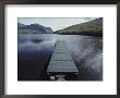 A Small Dock Leads Out To Placid Waters Of A Mountain Lake by Bill Curtsinger Limited Edition Print