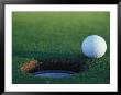 Golf Ball Poised At Edge Of Hole by Fogstock Llc Limited Edition Print