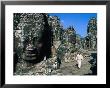 Buddhist Nun Walking Amongst Massive Stone Faces In Temple Grounds Of Bayon, Angkor Thom, Cambodia by Bill Wassman Limited Edition Print