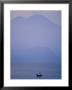 A Lone Boat Plies A Mountain Lake In Early Morning Fog by Raul Touzon Limited Edition Pricing Art Print