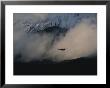 A Silhouetted Helicopter Flies Over A Smoldering Crater by Peter Carsten Limited Edition Print