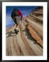 A Hiker On A Sandstone Cliff Patterned By Sedimentary Layers by Bill Hatcher Limited Edition Print