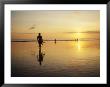 A Surfer With A Surfboard In Hand Walks Toward The Ocean At Sunset by Eightfish Limited Edition Print