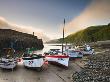 Fishing Vessels Beached At Low Tide In Clovelly Harbour, Devon, England by Adam Burton Limited Edition Print