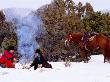 Cowboy With Cowgirl Sitting Near Camp Fire In Snow, Their Horse Standing Nearby, U.S.A. by Curtis Martin Limited Edition Print