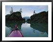 Reflection In Water Of Man Climbing On Large Rocks Near A Sea Kayak by Kate Thompson Limited Edition Print
