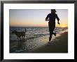 A Woman And Her Dog Run On The Beach At Sunset by Skip Brown Limited Edition Pricing Art Print