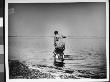 A Fully-Dressed Woman Wading At The Shore Of The Beach In Sag Harbor, Li, Ny by Wallace G. Levison Limited Edition Print