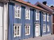 Row Of Colourful Homes (Blue, Red) On Street, Traditional Style With Timber Cladding by Andy Keate Limited Edition Pricing Art Print