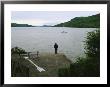 A Man Looks Out At A Sailboat Anchored On Otsego Lake by Raymond Gehman Limited Edition Pricing Art Print