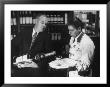 Pouring Champagne From A Huge Tilted Toward Glass Held On Tray By Waiter, At The Hotel Hilton by Ralph Crane Limited Edition Print