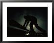 Silhouetted Oil Rig Worker Lifting A Pipe, Wyoming by Lynn Johnson Limited Edition Print