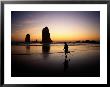 A Boy Runs Along Cannon Beach With Sea Stacks In The Background by Phil Schermeister Limited Edition Print