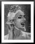 Woman Wearing Flowered Bathing Cap And Applying Mascara As Water Showers Around Her by Gjon Mili Limited Edition Pricing Art Print