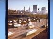 Blurred Traffic On Curving Stretch Of Highway With Skyscrapers In Distance by Ralph Crane Limited Edition Print